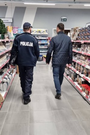 Na zdjęciu funkcjonariusz policji wraz z pracownikiem SANEPIDU w trakcie kontroli obiektu handlowego.