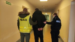 Na zdjęciu policjanci prowadzą zatrzymanego