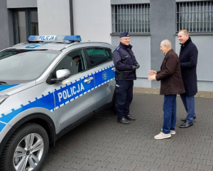 Na zdjęciu radiowóz i policjant odbierający kluczyki