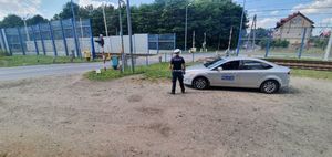 Na zdjęciu policyjny radiowóz i policjant przy przejeździe kolejowym