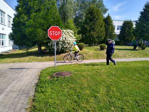 Na zdjęciu znak stop oraz policjant i dziecko na rowerze