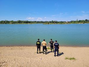 Na zdjęciu policjanci i strażacy na tle zbiornika wodnego