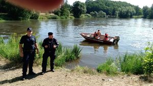 Na zdjęciu strażacy na pontonie i policjanci stojący na brzegu