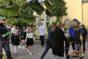 Na zdjęciu policjanci i policyjna maskotka przy szkole