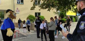 Na zdjęciu dzieci idące do szkoły i policjant z maskotka