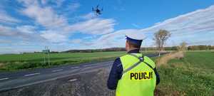 Na zdjęciu funkcjonariusz policji sterujący dronem unoszącym się nad jezdnią w trakcie nadzoru nad ruchem na jednej z zgorzeleckich dróg.