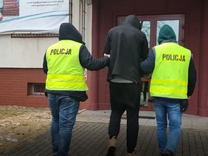 Na zdjęciu policjanci prowadzący zatrzymanego