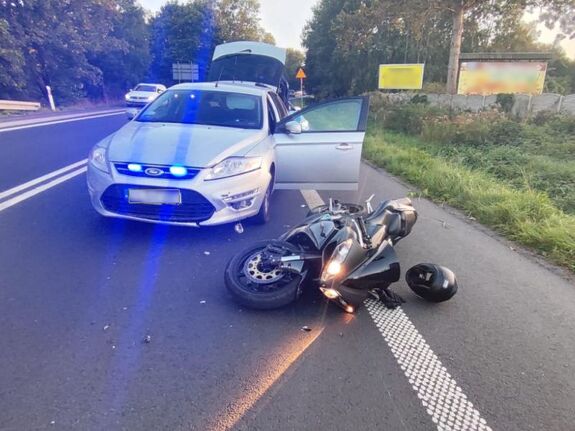 Na zdjęciu motocykl leżący na jezdni i nieoznakowany radiowóz