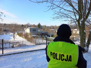 Na zdjęciu policjant na tle ogrodów działkowych