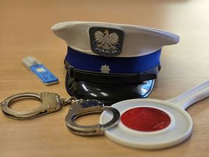 Na zdjęciu policyjna czapka, kajdanki i tester narkotykowy