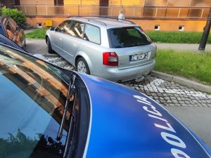 Na zdjęciu maska radiowozu i nieprawidłowo zaparkowany pojazd