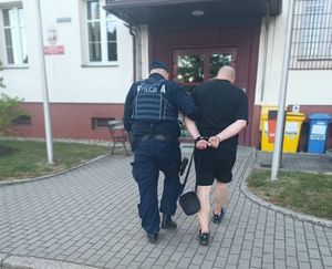 na zdjEciu policjant prowadzący zatrzymanego