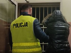 Na zdjęciu policjant prowadzący zatrzymanego