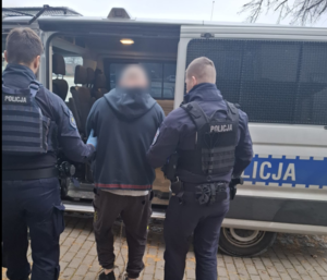 Na zdjęciu policjanci prowadza zatrzymanego