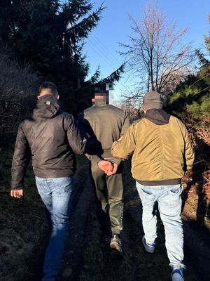 Na zdjęciu policjanci prowadzą zatrzymanego