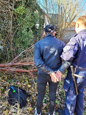 Na zdjęciu policjanci prowadzą zatrzymanego