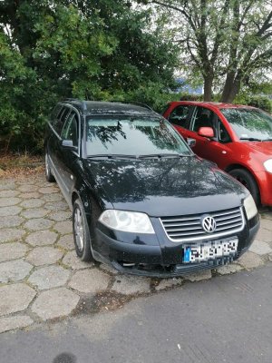 Pojazd marki Volkswagen koloru granatowego zaparkowany na kostce brukowej. W tle widać pojazd osobowy koloru czerwonego.