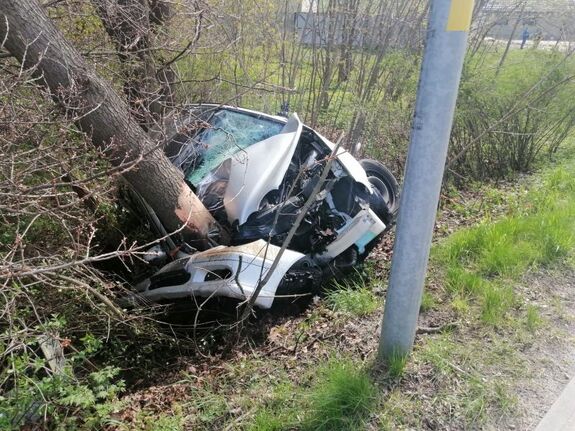Na zdjęciu pojazd lezący w rowie z rozbita maską, który uderzył w drzewo.