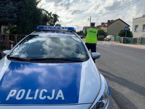 Na zdjęciu policyjny radiowóz i policjant przy przejściu dla pieszych